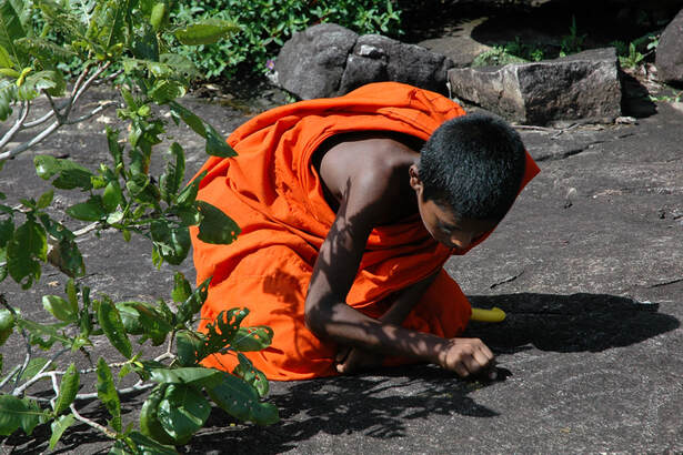 young Buddhist novice writing on the rock of Dimbulagala