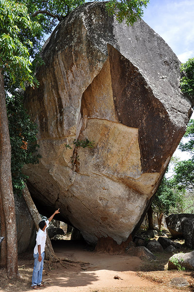 Touristenfphrer in Mihintale zeigt zu einer Felsinschrift